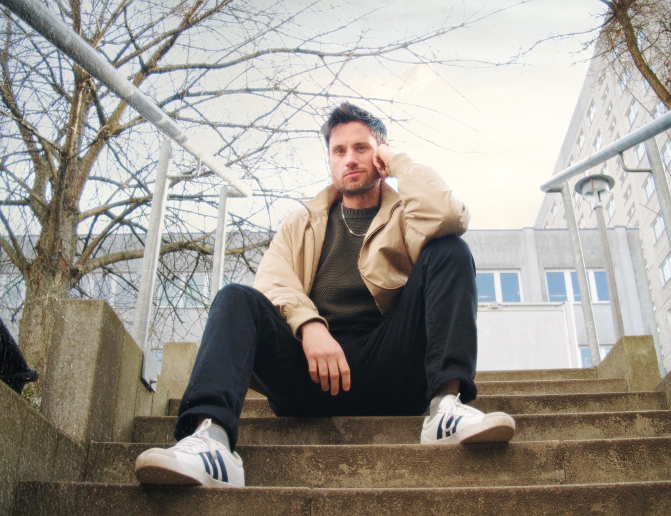 Videofreelancer Patrick Winzler sitzt auf einer Treppe in Berlin
